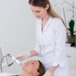 young woman getting facial treatment in cosmetology salon